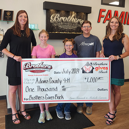Lynn & Michelle, The Sisters from Brothers, presenting a check of $1,000 to three children with Adams County 4-H.